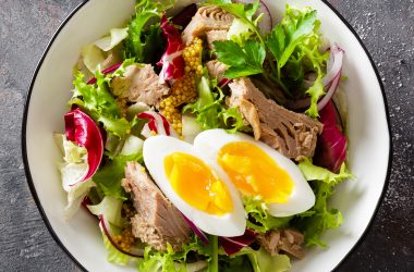Diet food tuna salad with boiled egg, canned fish, onion and green lettuce top view